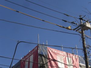 足場を設置すると電線が接近してしまうため、写真の黄色の防護カバーを電線に取り付け安全に配慮しております。